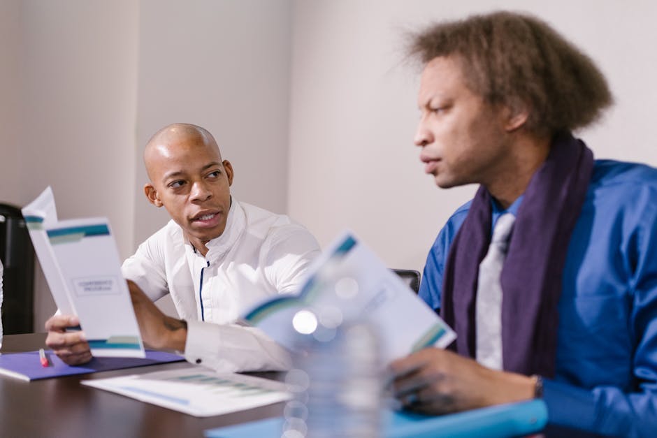 Two professionals engaged in a focused discussion during a business meeting in a conference room.